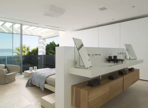 Modern bedroom with open layout, white partition wall, wooden desk with computer monitors, ocean view windows
