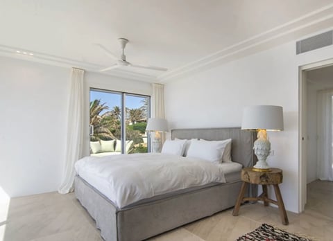 Bright modern bedroom with gray upholstered bed and garden view