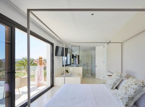Modern bedroom with sliding glass doors opening to a terrace, ensuite bathroom