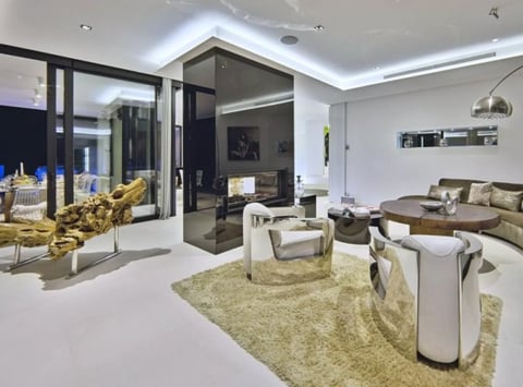 Modern luxury living room with beige furnishings, gold accents, glass partitions, and LED ceiling lights