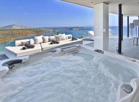 Luxurious modern terrace with a hot tub overlooking a Mediterranean coastal landscape and blue sea