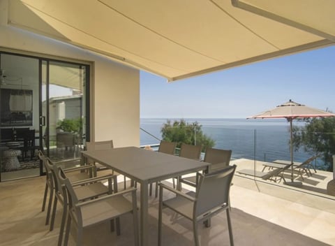 Modern waterfront terrace with dining table under retractable awning