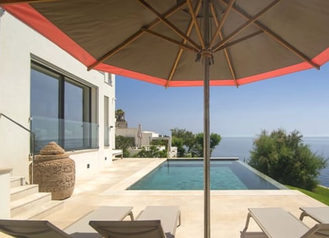 Luxury terrace with infinity pool, lounge chairs, and sea view
