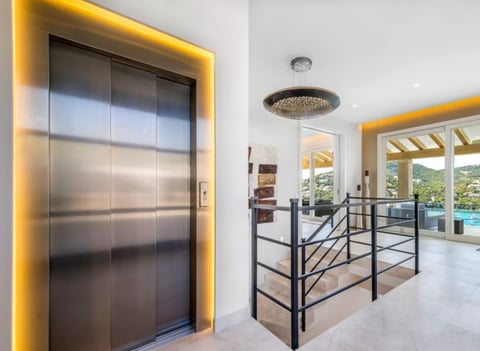 Modern entryway with illuminated gold-framed elevator and open floor plan