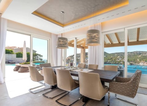 Modern dining room with beige chairs and wooden table overlooking sea view