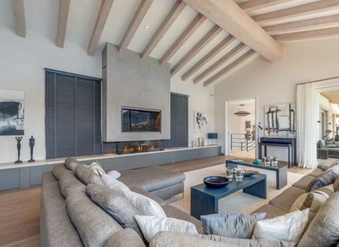Modern living room with vaulted ceiling, fireplace, and neutral upholstered seating