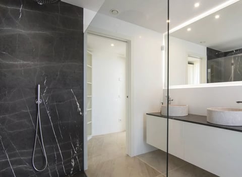 Modern bathroom with dark marble shower and white vanity