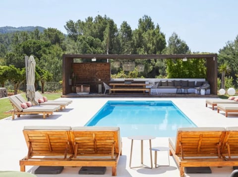 Modern backyard with rectangular swimming pool, wooden loungers, and brick pergola