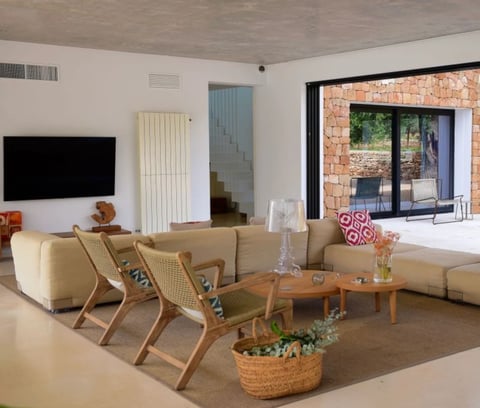 Modern living room with beige sectional sofa, wooden accent chairs, wall-mounted TV