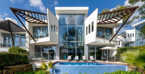 Modern luxury white villa with geometric architecture, swimming pool, pergolas, and tropical landscaping under blue sky