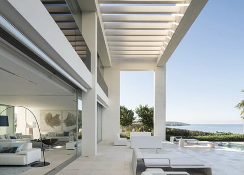 Modern white villa terrace with pergola, lounge chairs, and panoramic sea view