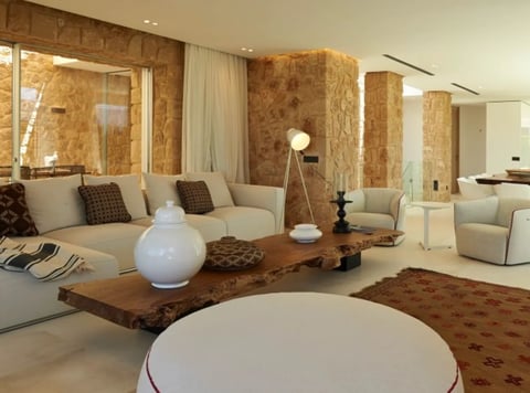 Modern luxury living room with cork walls, beige curved seating, rustic wood table, and minimalist decor