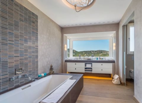 Modern bathroom with soaking tub, tiled accent wall, and floating vanity