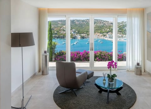 Modern living room with gray chair and round table facing large windows overlooking Mediterranean sea