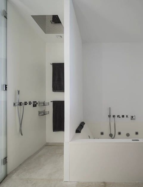 Modern minimalist bathroom with walk-in shower, rainfall showerhead, black towel rack, and soaking tub